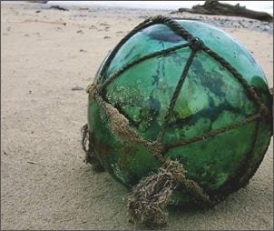 A large old Japanese green glass fishing float, complete with its